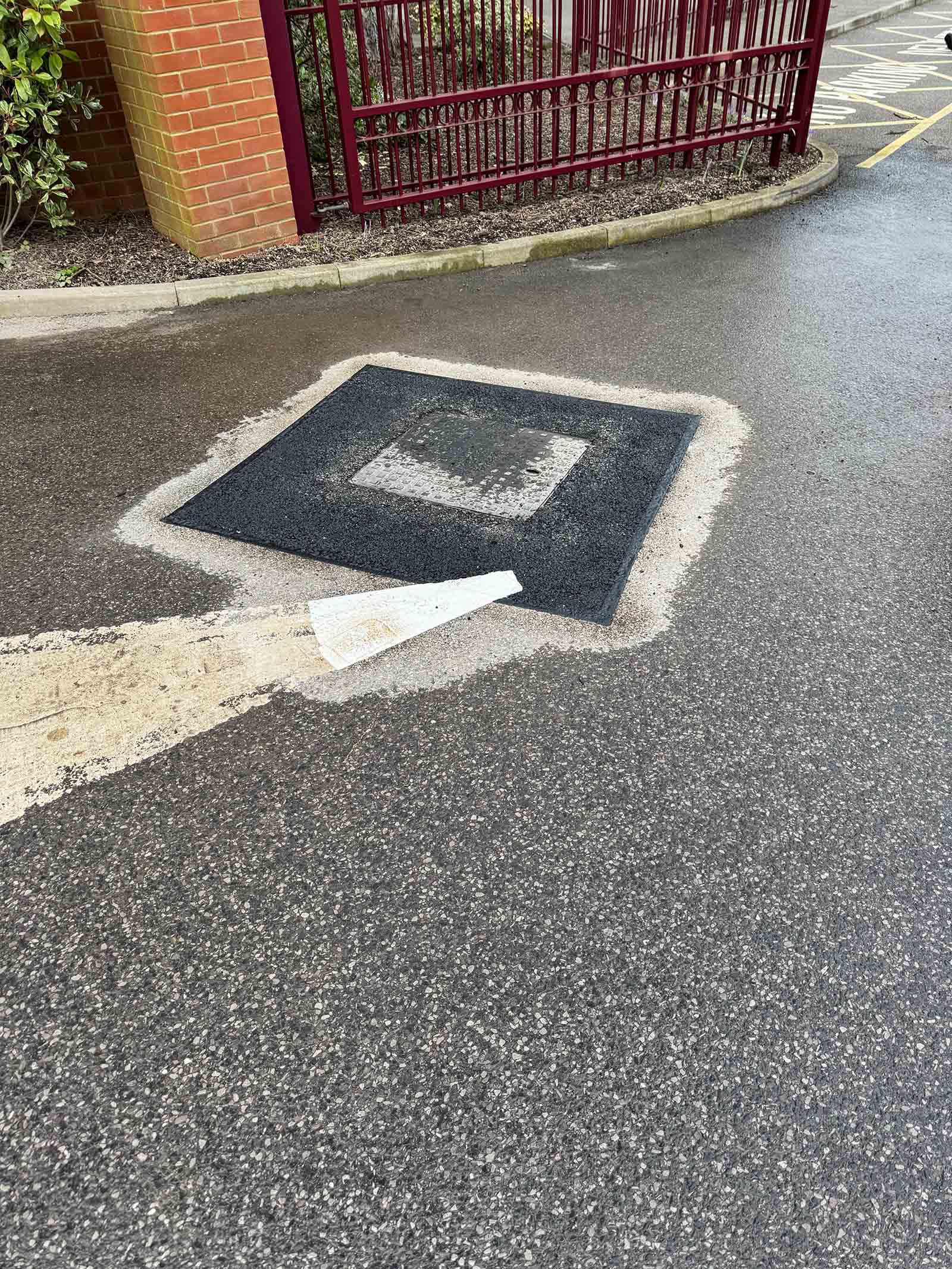 Tarmac surface repair around utility cover in Weybridge