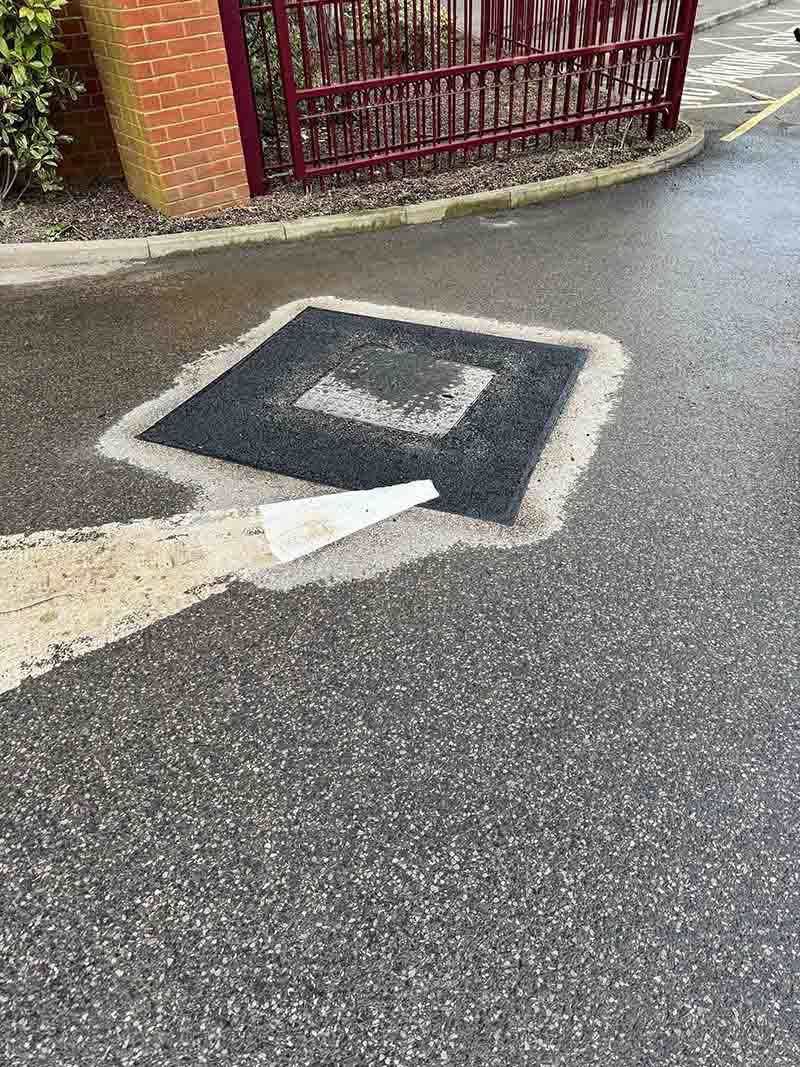 Tarmac surface repair around utility cover in Weybridge